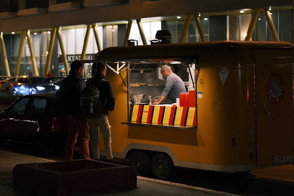 a couple of people standing outside of a food truck