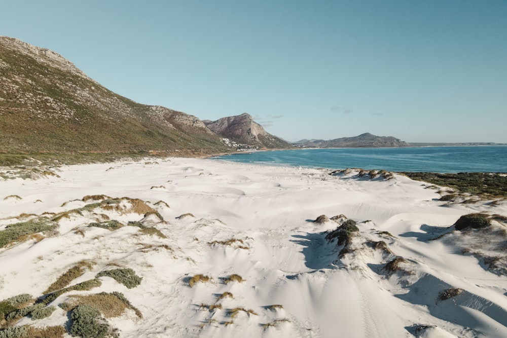 a beach covered in snow next to a mountain