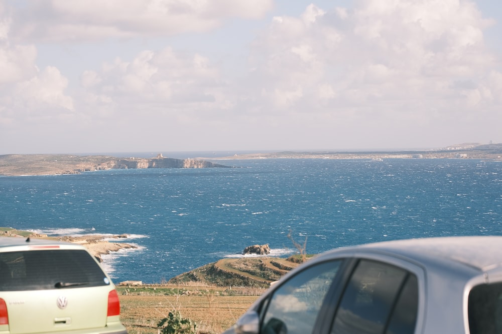 two cars parked on the side of a road near a body of water