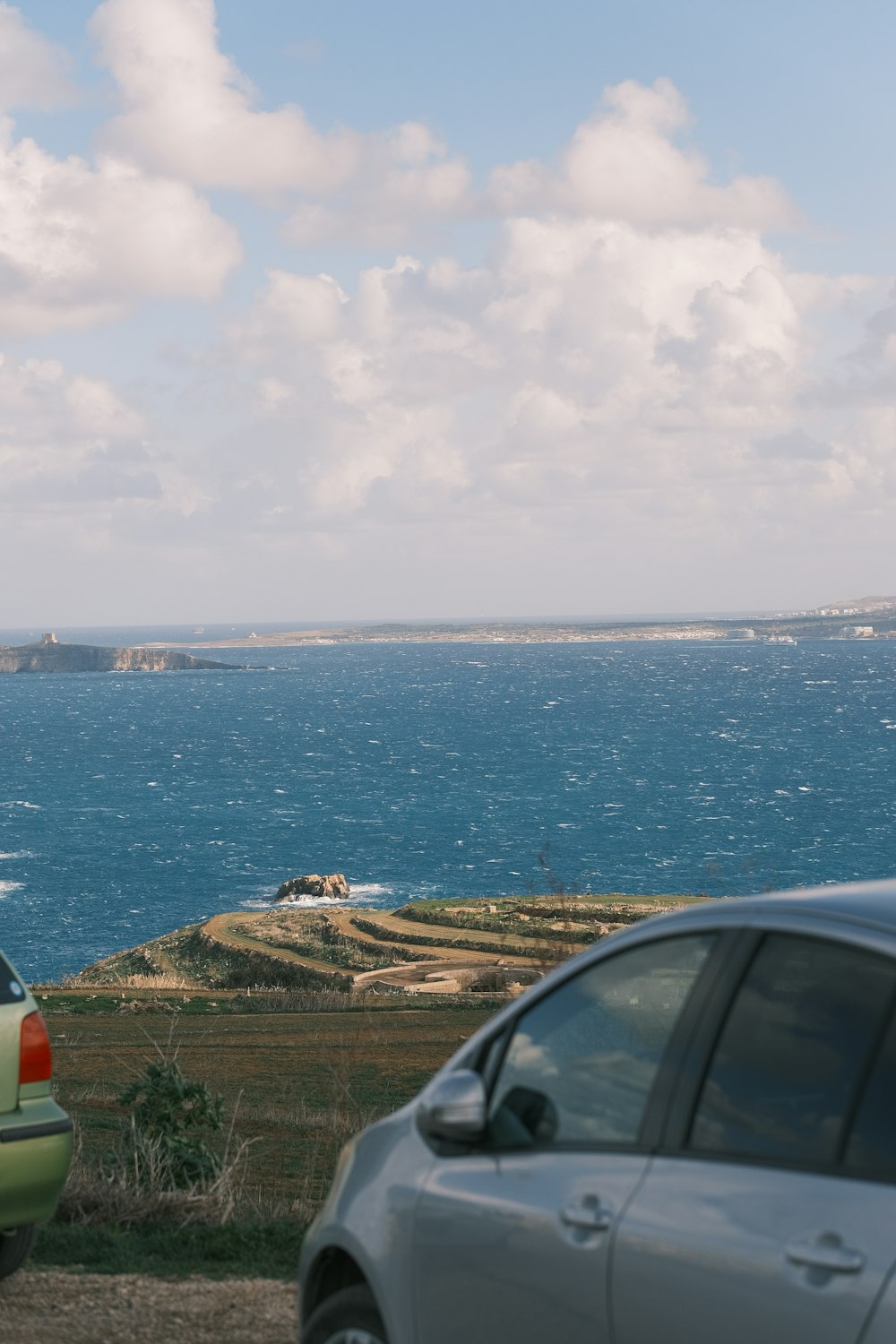 two cars parked next to each other near the ocean