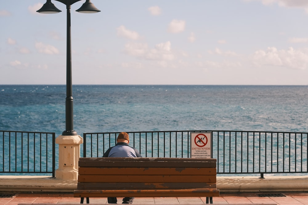 a man sitting on a bench next to the ocean