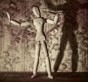 a wooden mannequin standing in front of a wall