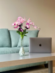 a vase of flowers sitting on a table next to a laptop