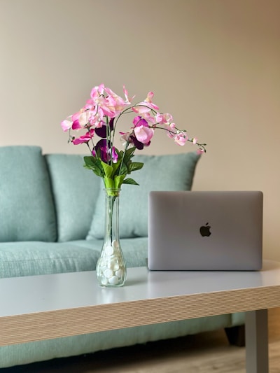 a vase of flowers sitting on a table next to a laptop
