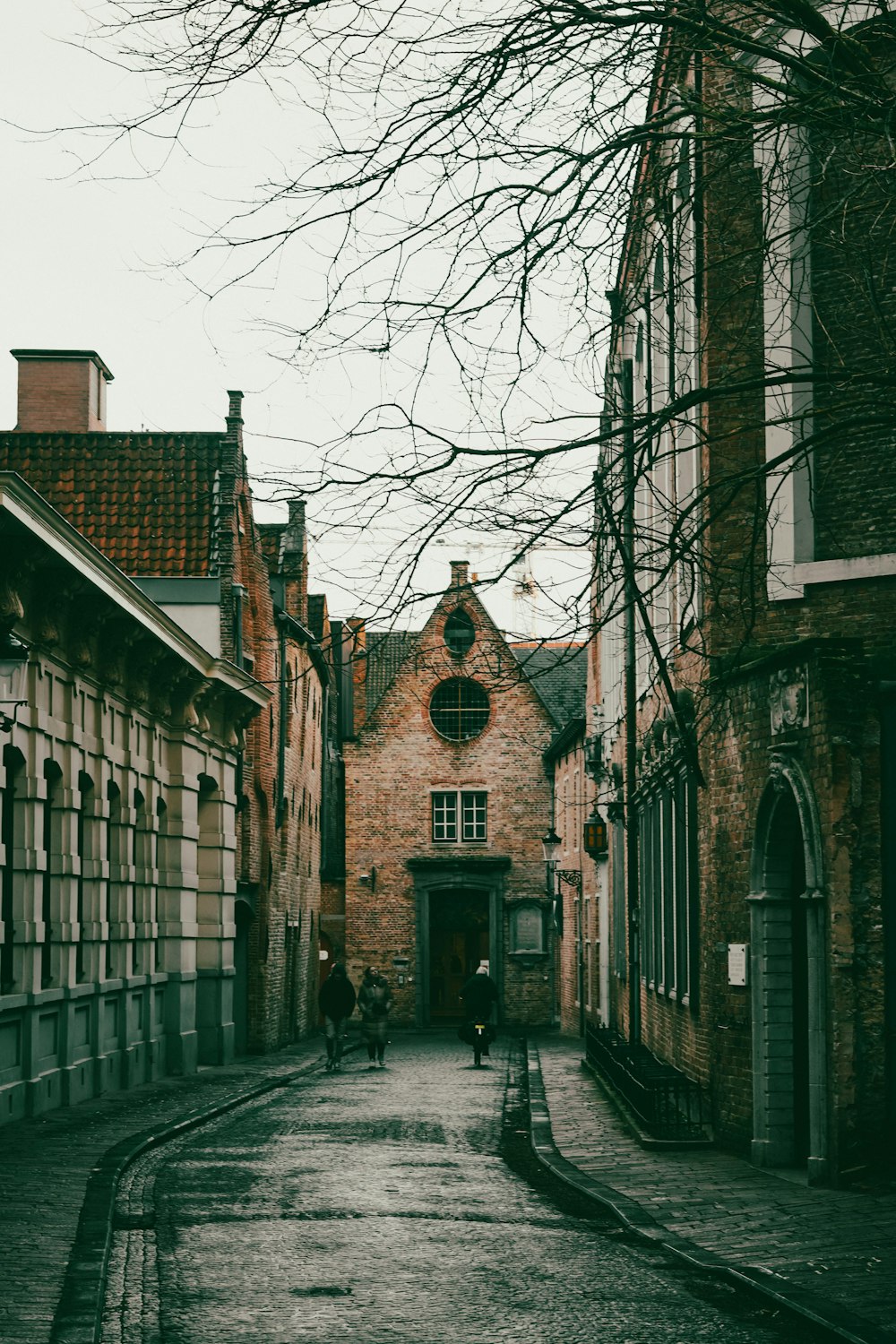 a couple of people walking down a street next to tall buildings