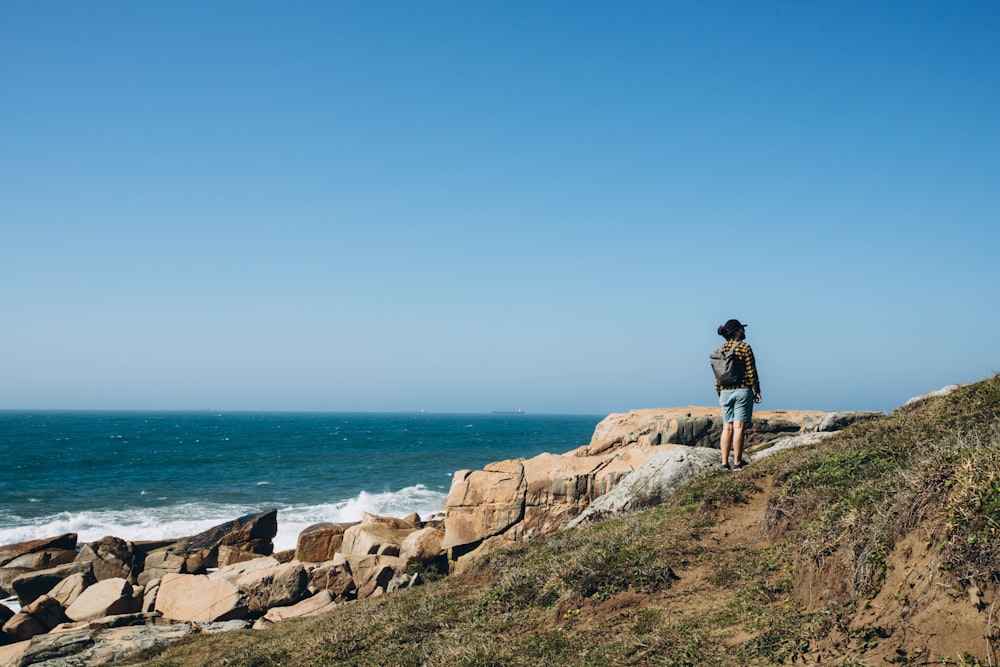 a person standing on top of a rocky cliff next to the ocean
