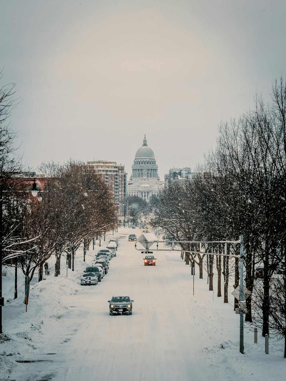 a snowy street with cars parked on the side of it