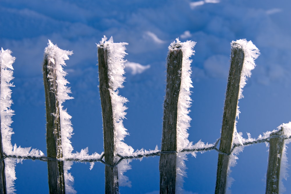 a fence covered in snow against a blue sky