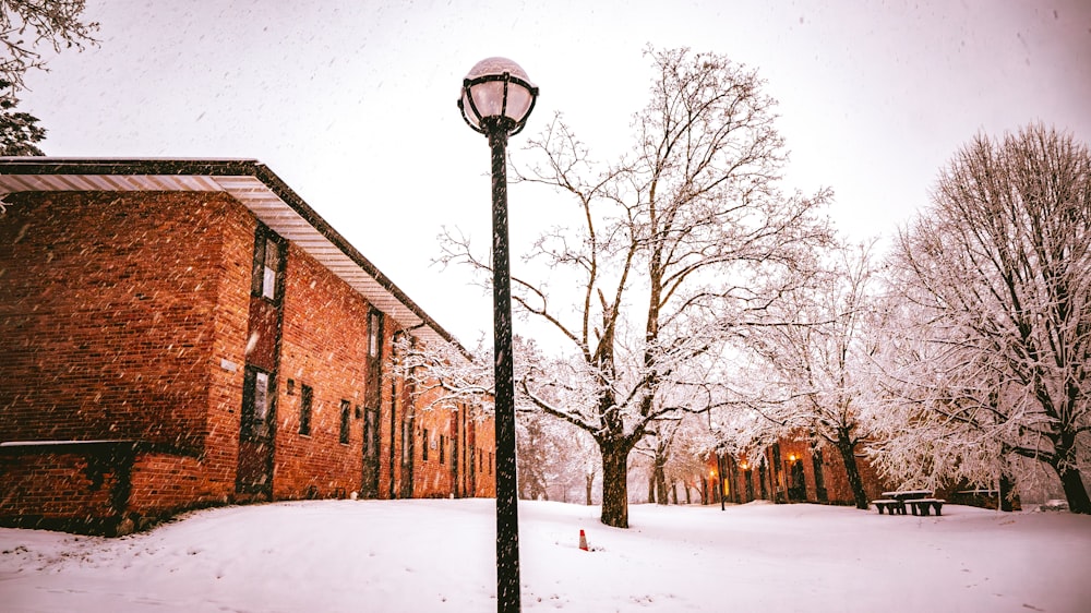 a street light on a snowy street next to a brick building