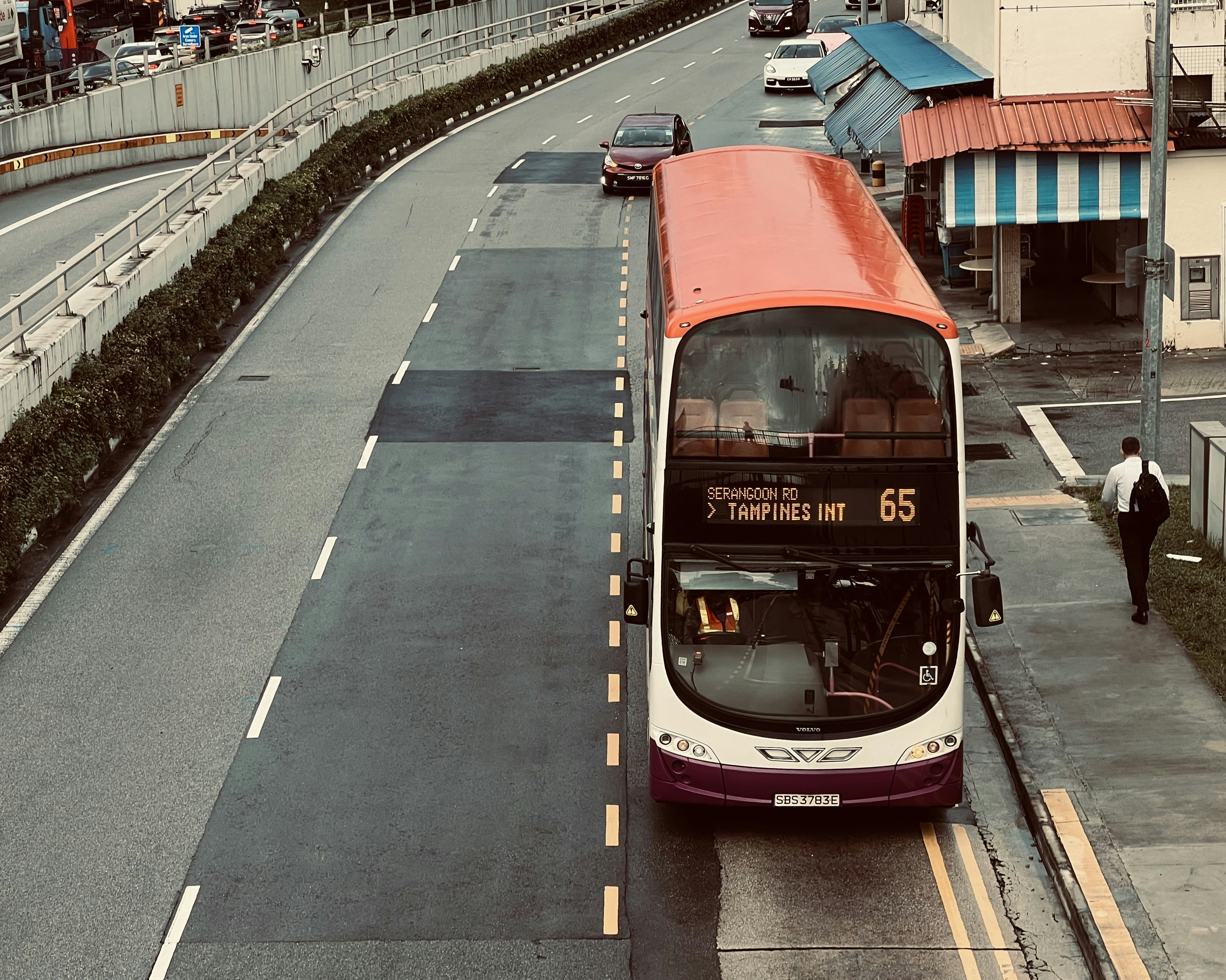 a red and white double decker bus driving down a street