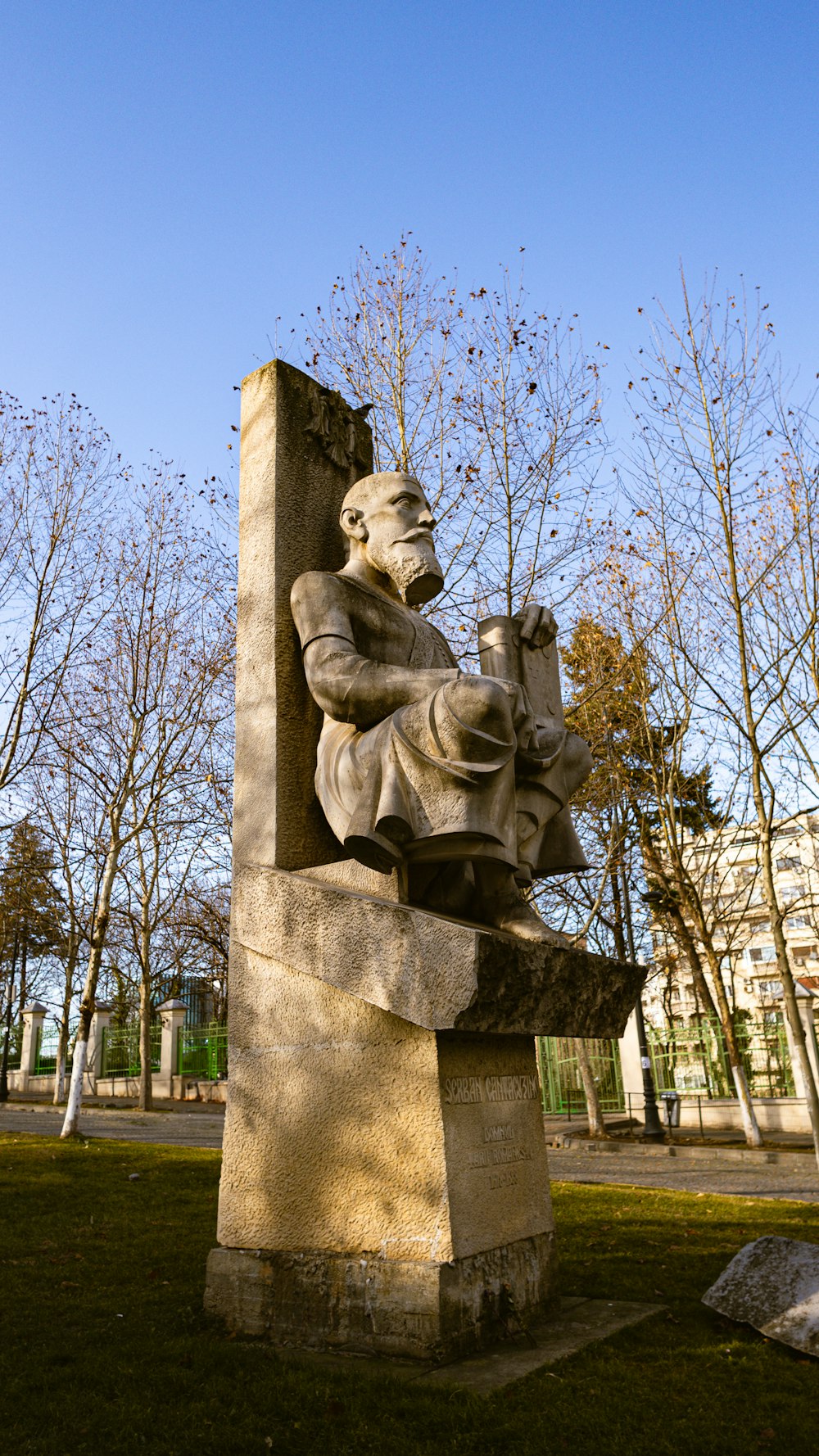 una statua di un uomo che legge un libro in un parco