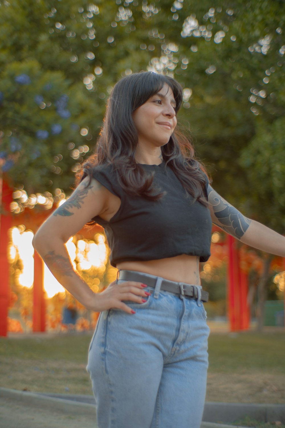 a woman standing in a park with her hands on her hips