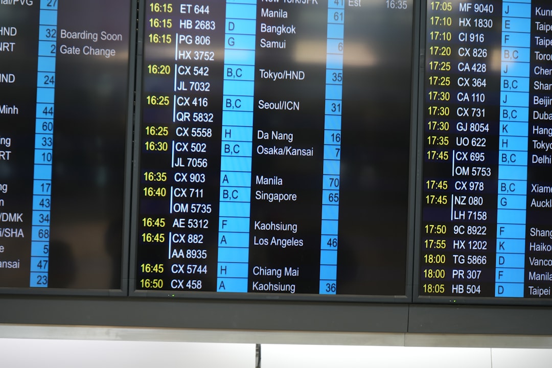 a large screen displaying a flight schedule at an airport, Hong Kong International Airport.