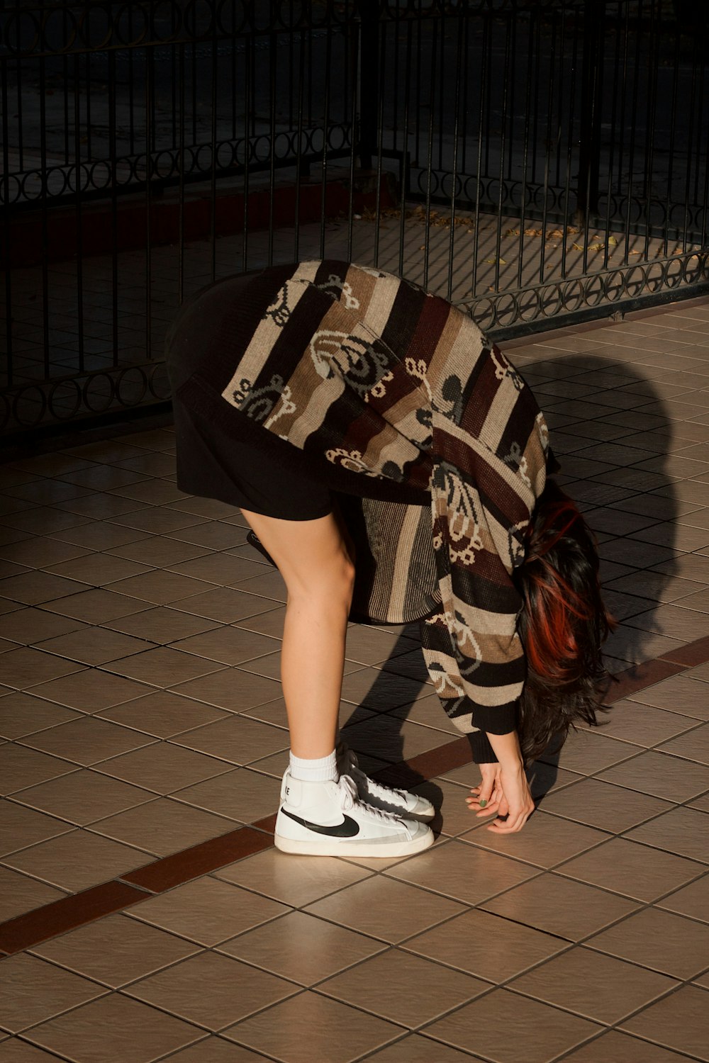 a woman bending over on a skateboard on a tiled floor