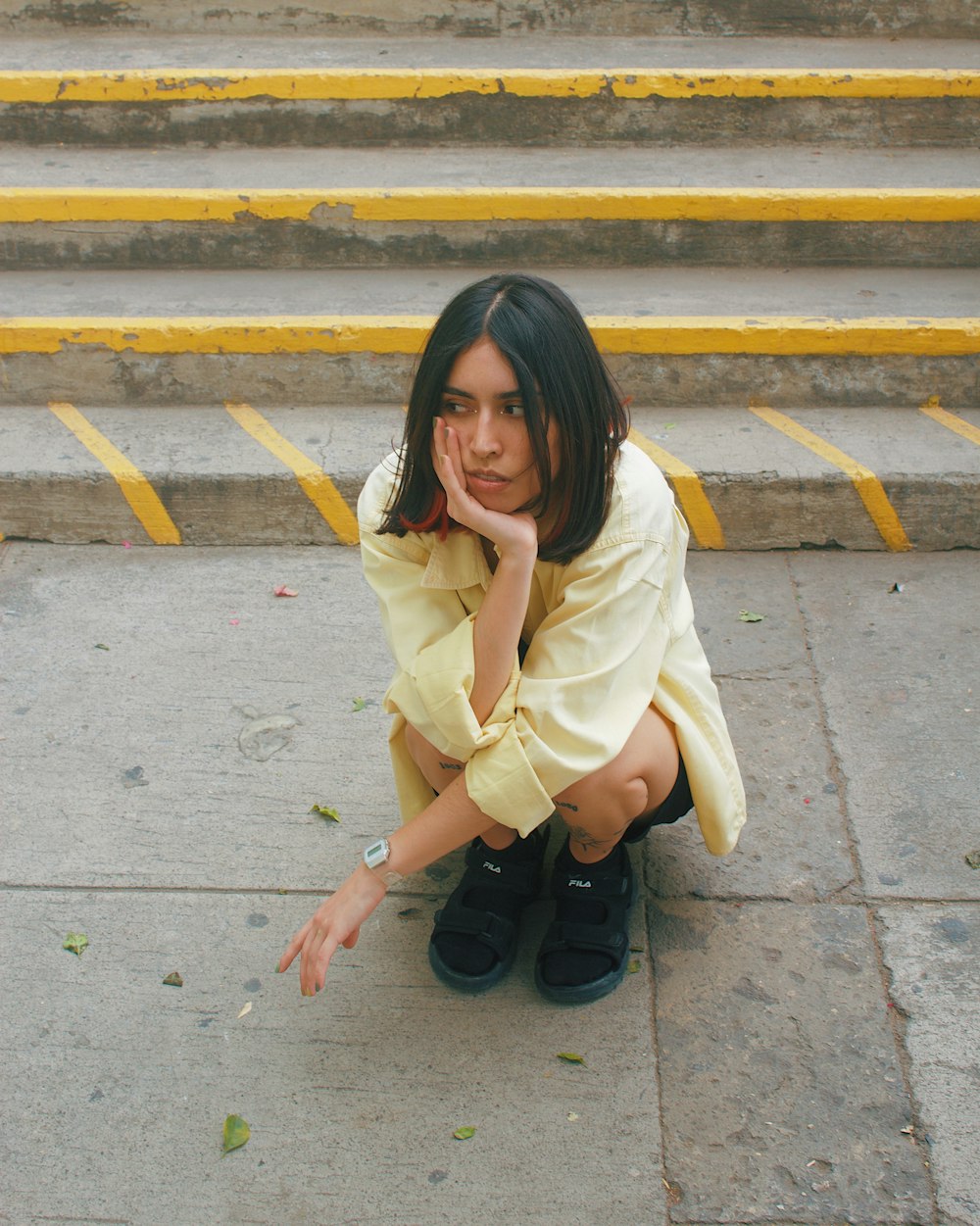 a woman sitting on the ground with her hand on her face