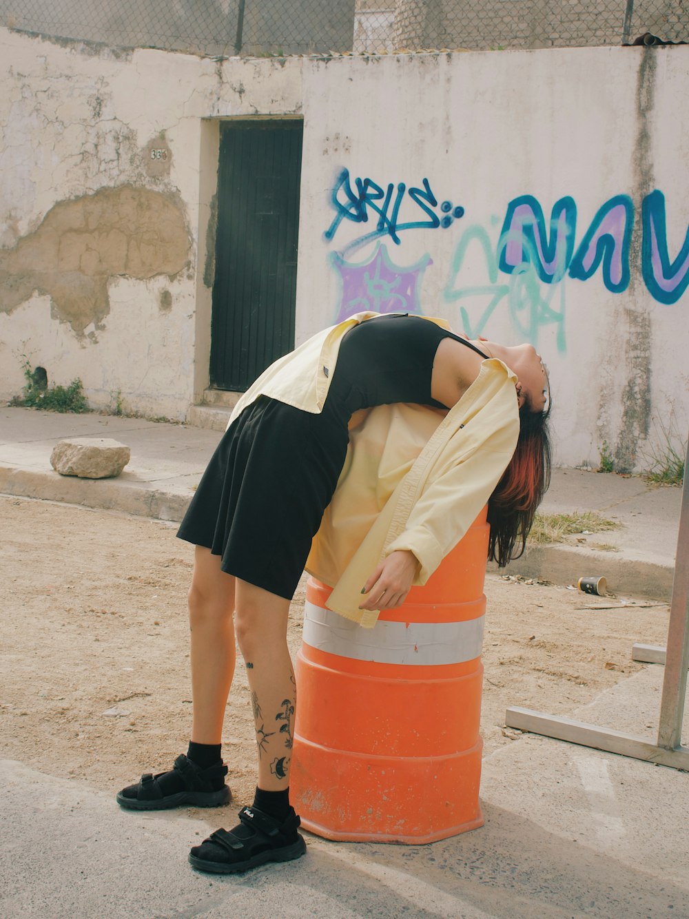 a woman leaning over a traffic cone on the side of the road