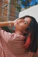 a woman in a striped shirt is holding her hand on her head