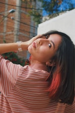a woman in a striped shirt is holding her hand on her head