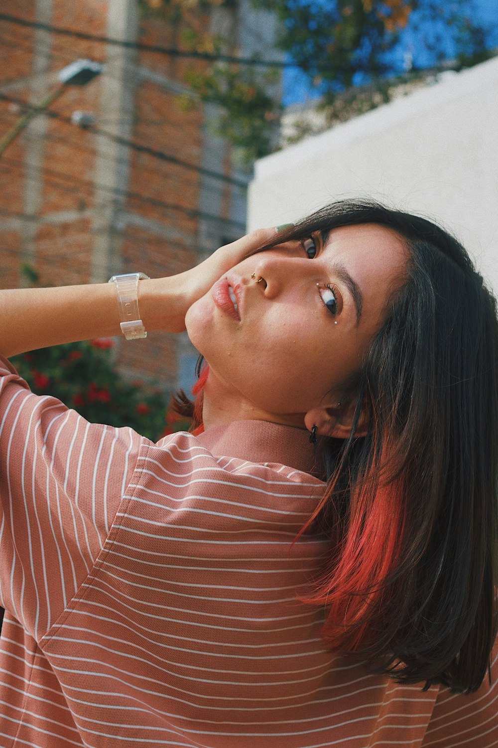 a woman in a striped shirt is holding her hand on her head