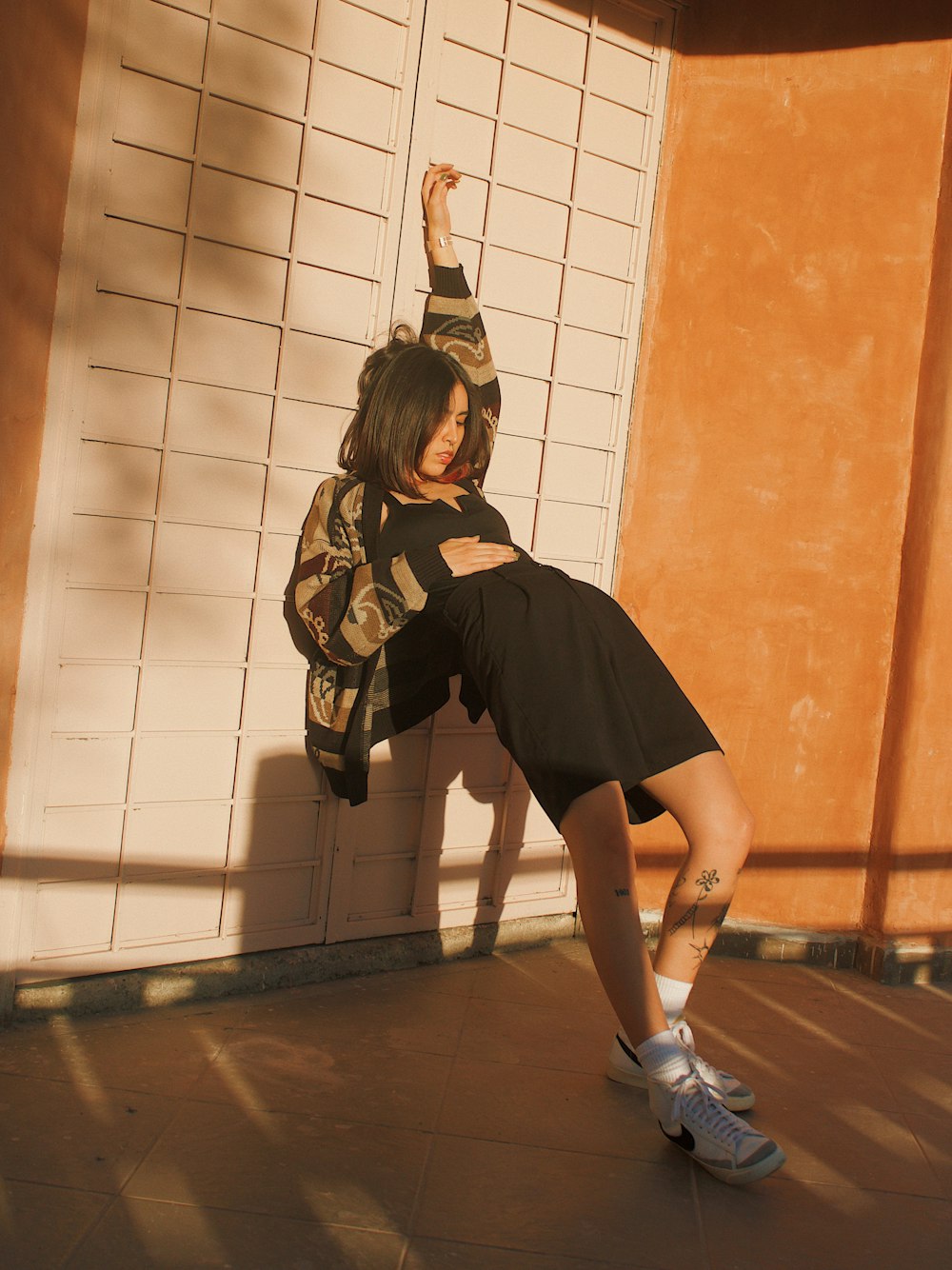 a woman in a black dress leaning against a wall