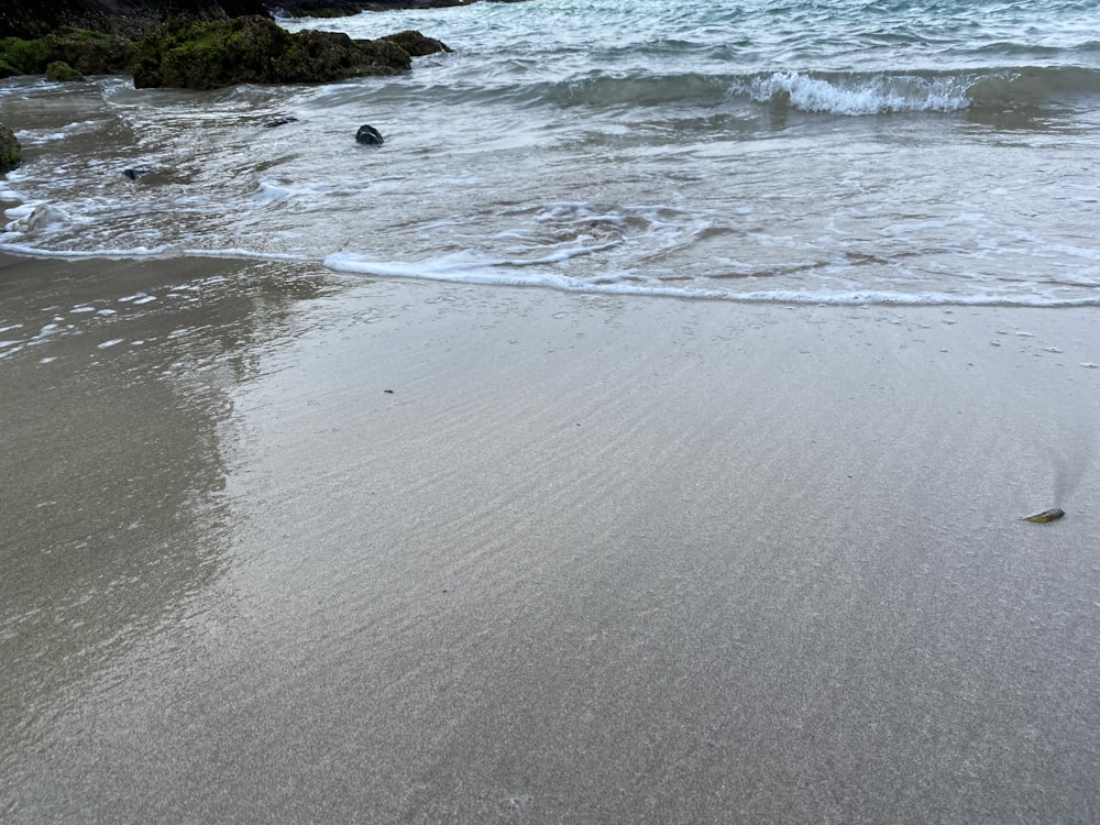 a sandy beach with waves coming in to shore