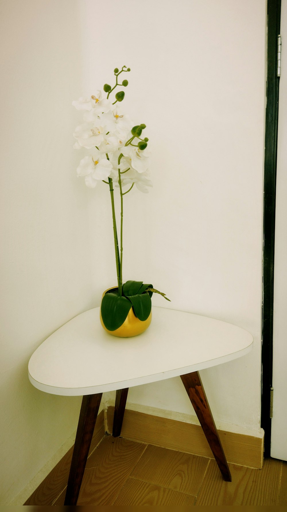 a white table with a yellow vase with flowers on it