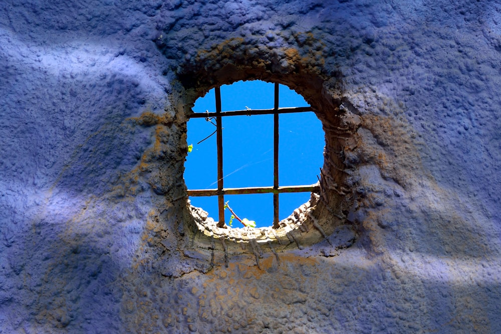 a hole in a cement wall with a blue sky in the background