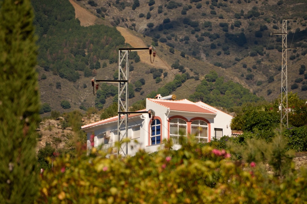 a white house with a red roof and a mountain in the background