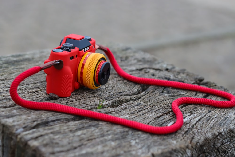 a red camera sitting on top of a piece of wood