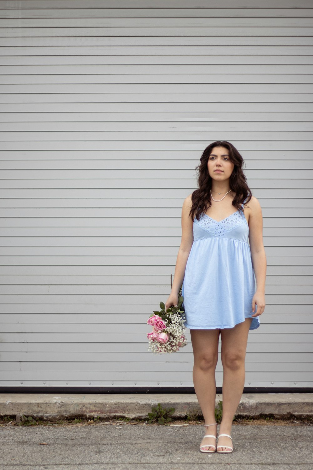 a woman standing in front of a garage door holding a bouquet of flowers