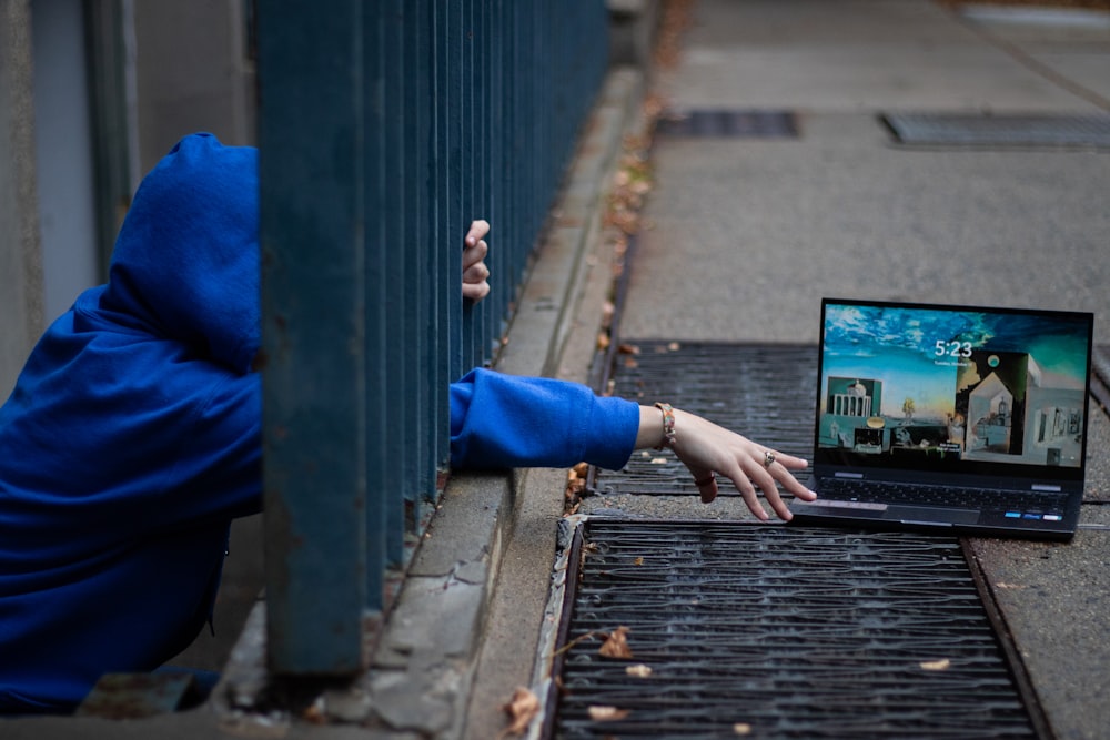 a person in a blue hoodie using a laptop