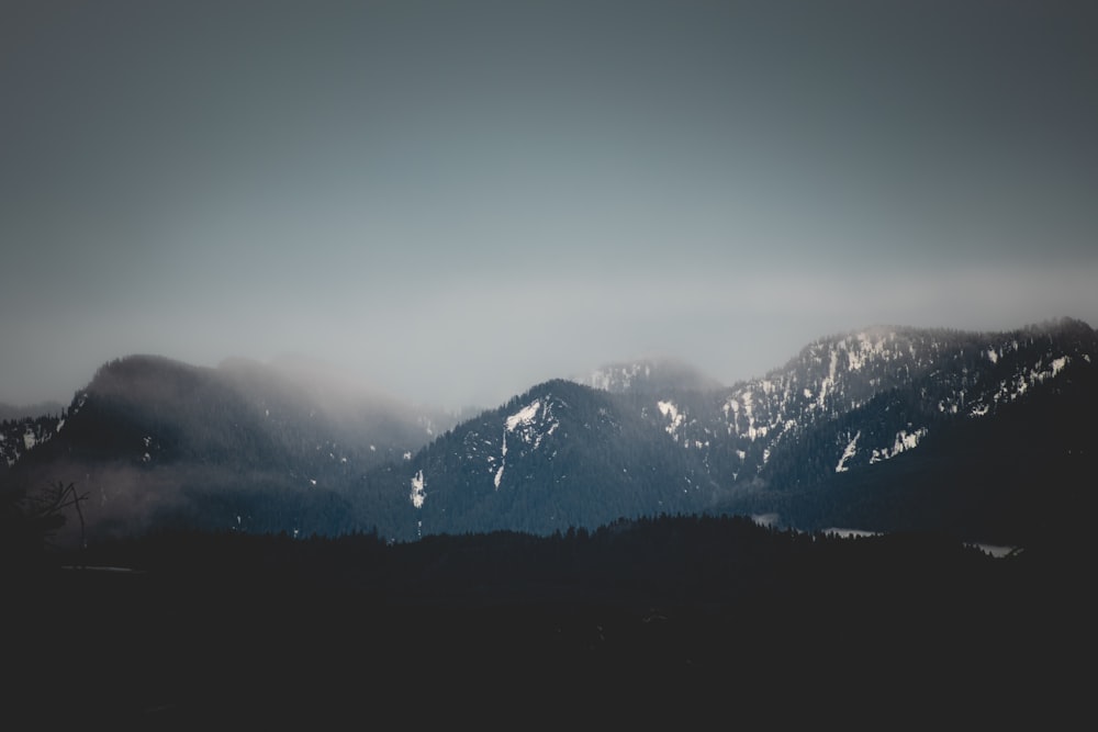 a mountain range covered in snow and clouds