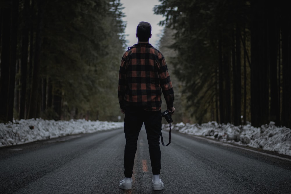 a man walking down a road holding a camera