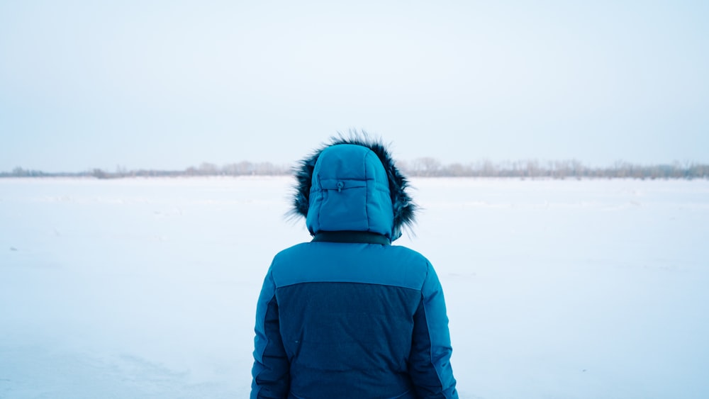 uma pessoa em pé na neve vestindo uma jaqueta azul