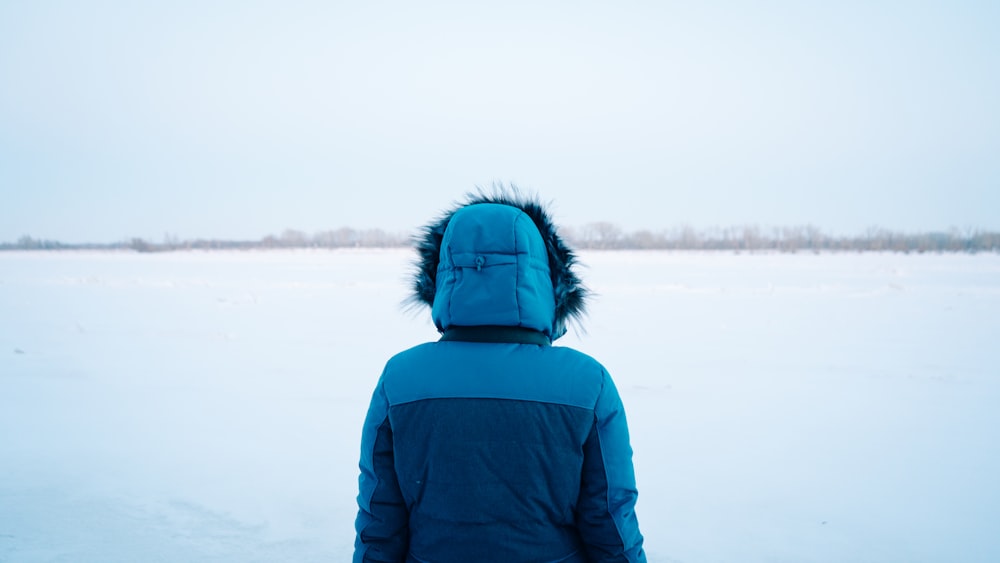 una persona in piedi nella neve che indossa una giacca blu