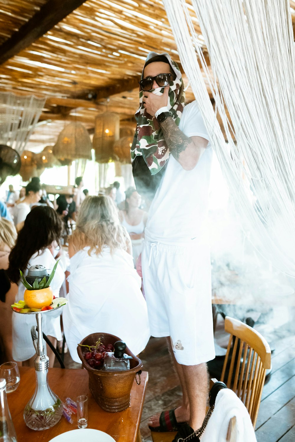 a man in white shorts and sunglasses standing in front of a table