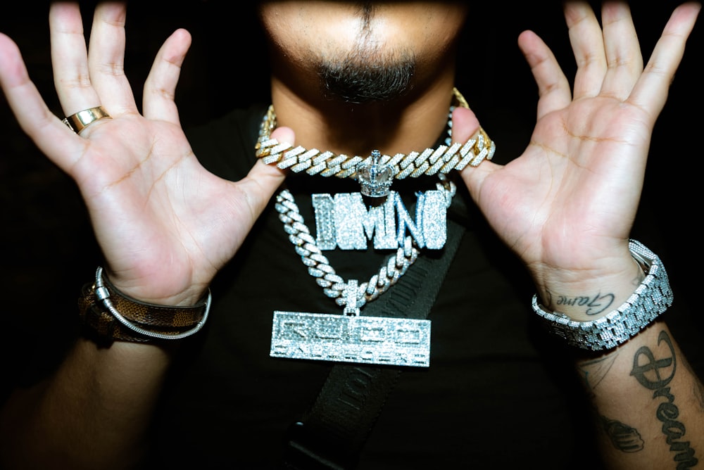 a man holding his hands up with a chain around his neck