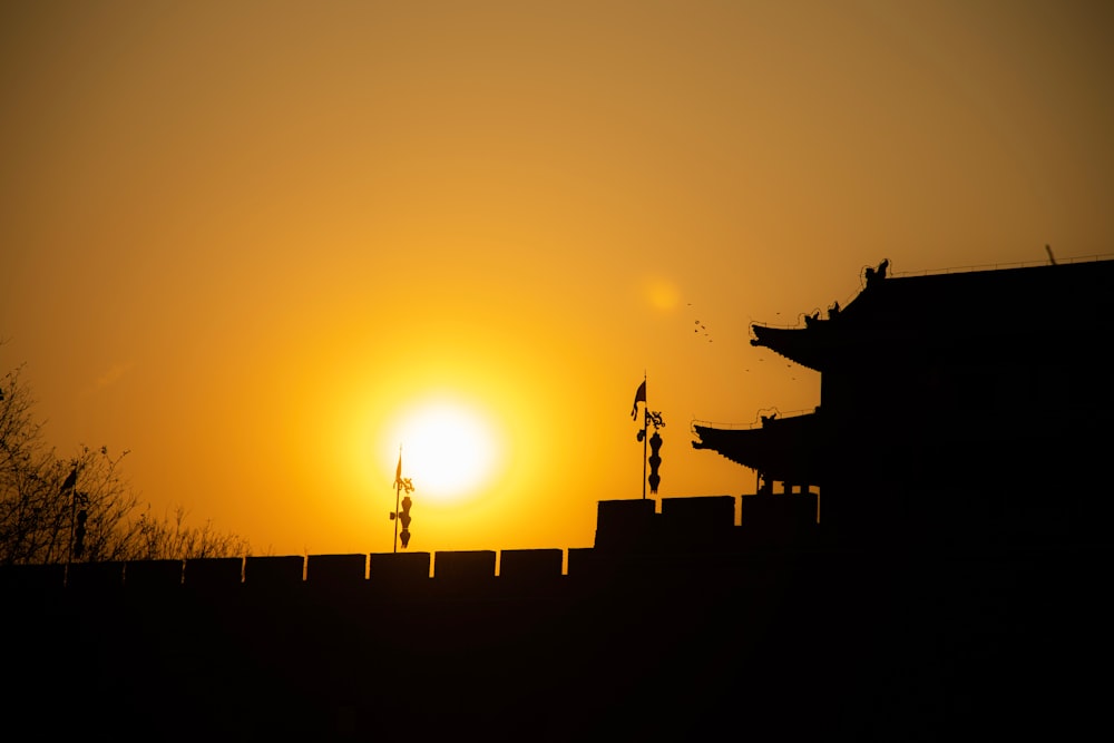 the sun is setting behind a building with a roof