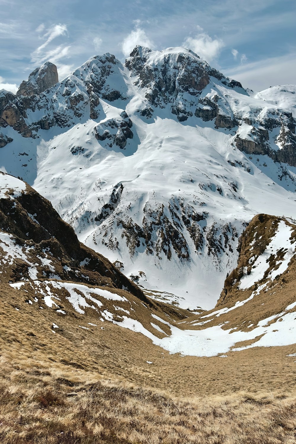 a snow covered mountain range with a few clouds in the sky