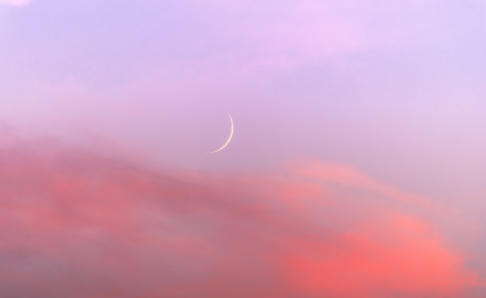 a pink and purple sky with a crescent moon