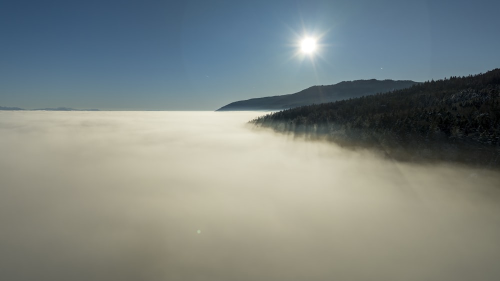 the sun is shining over a foggy valley