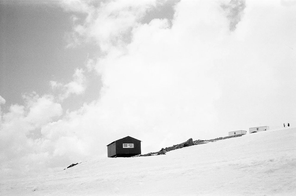 a black and white photo of a house on a snowy hill