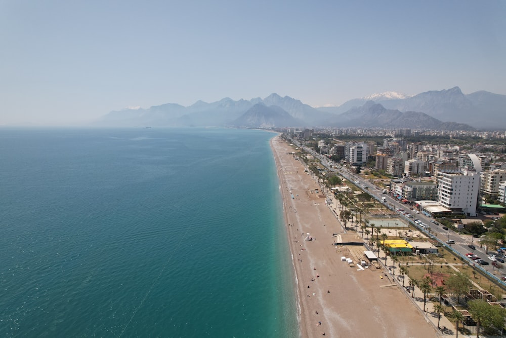 an aerial view of a beach with mountains in the background