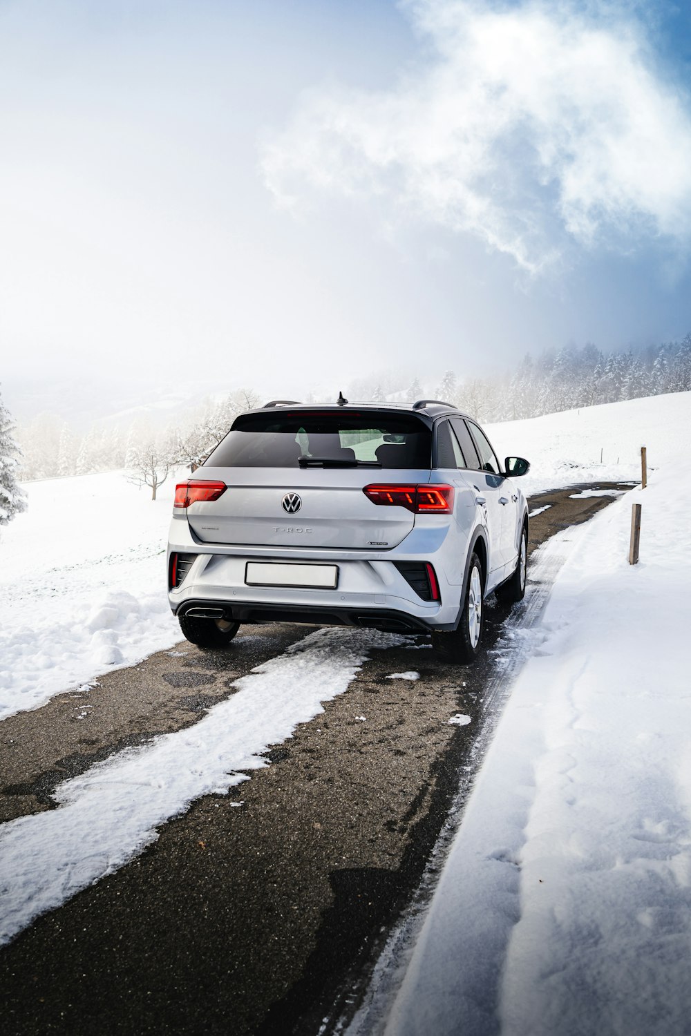 a white car driving down a snow covered road