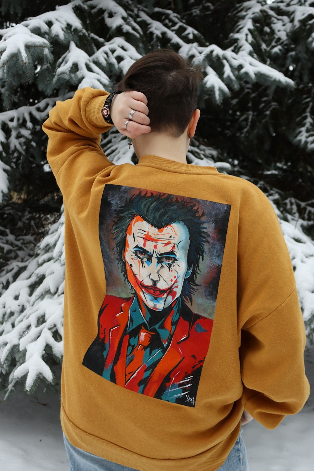 a man wearing a sweatshirt with a painting of a joker on it