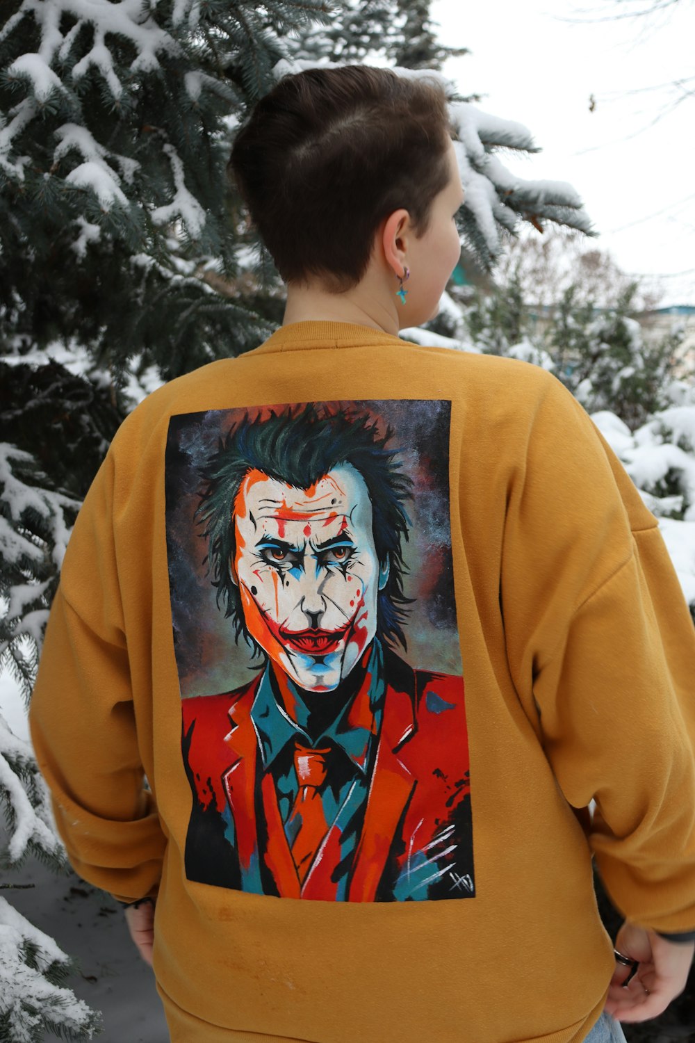a young boy wearing a sweatshirt with a painting of a joker on it