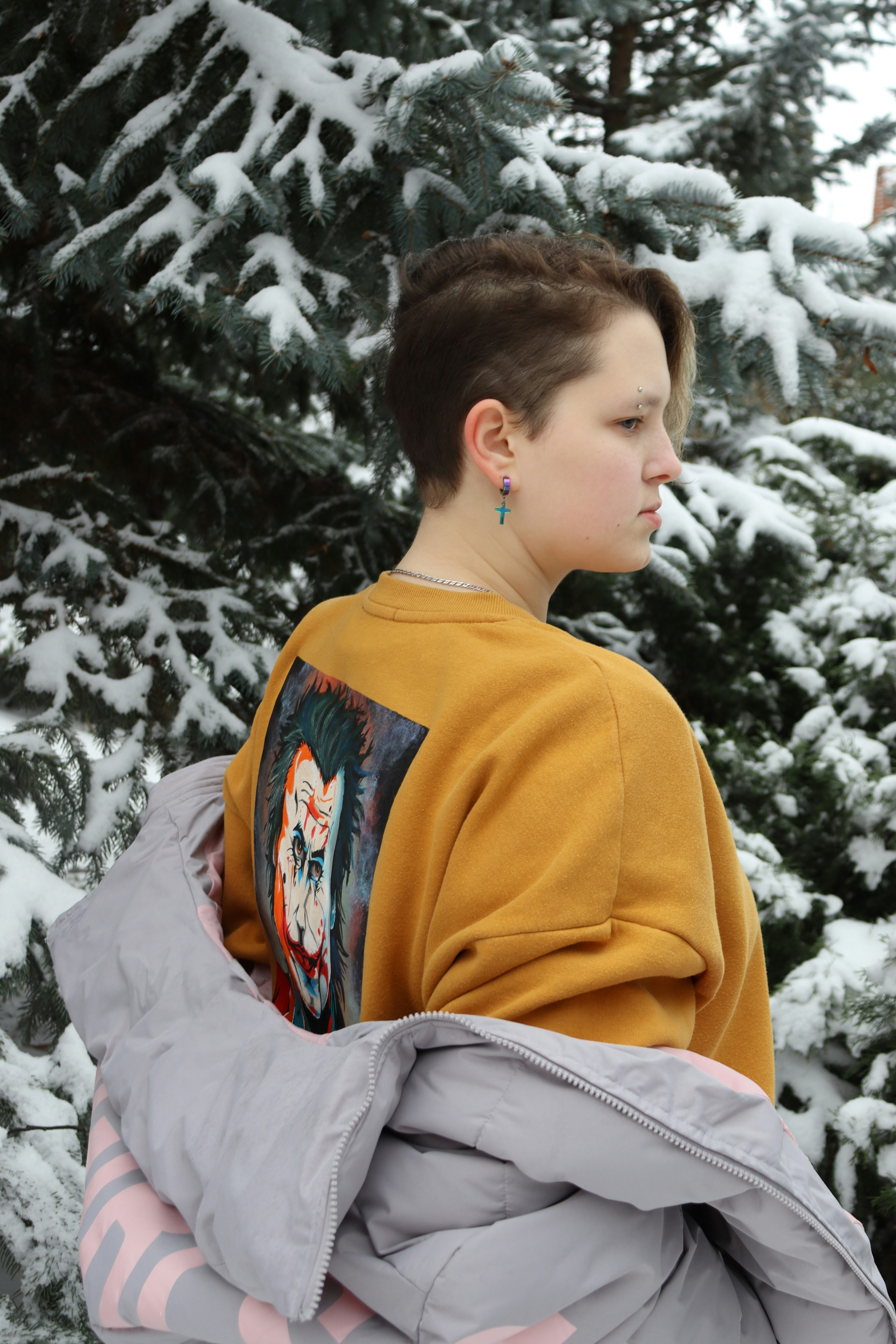 a young boy standing in front of snow covered trees