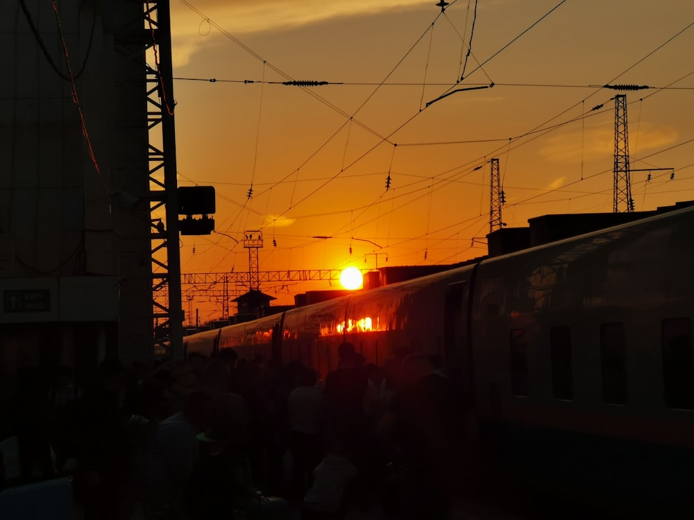 the sun is setting behind a train on the tracks