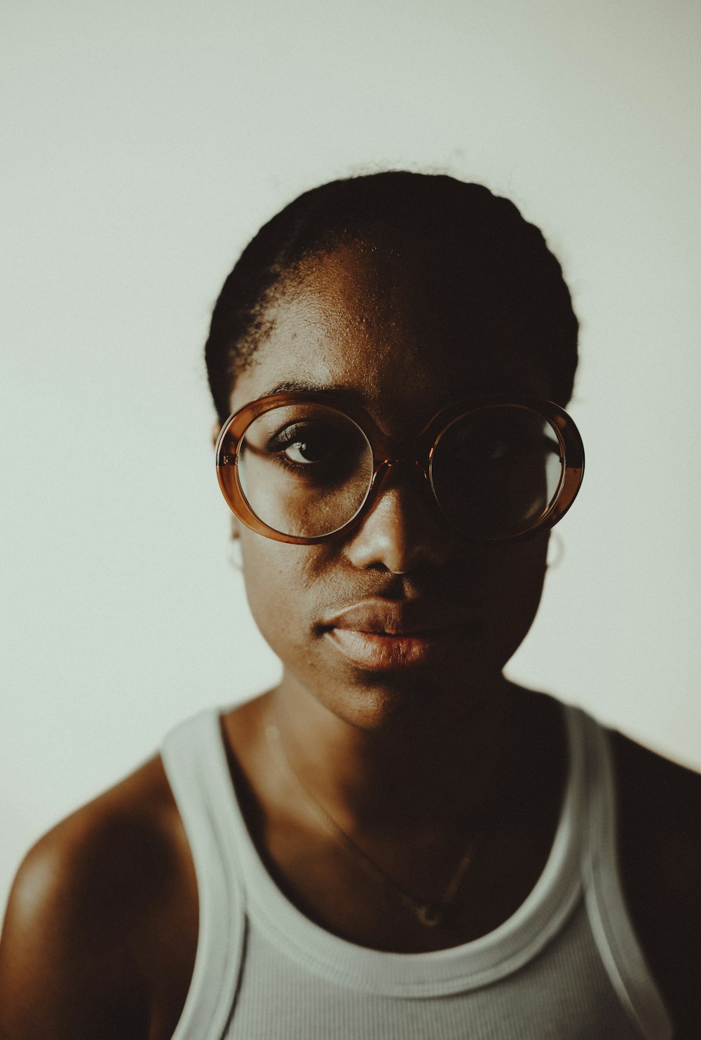 a woman wearing glasses and a tank top