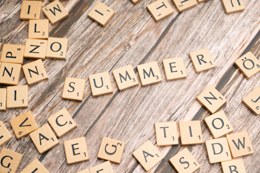 scrabble tiles spelling the word summer on a wooden surface